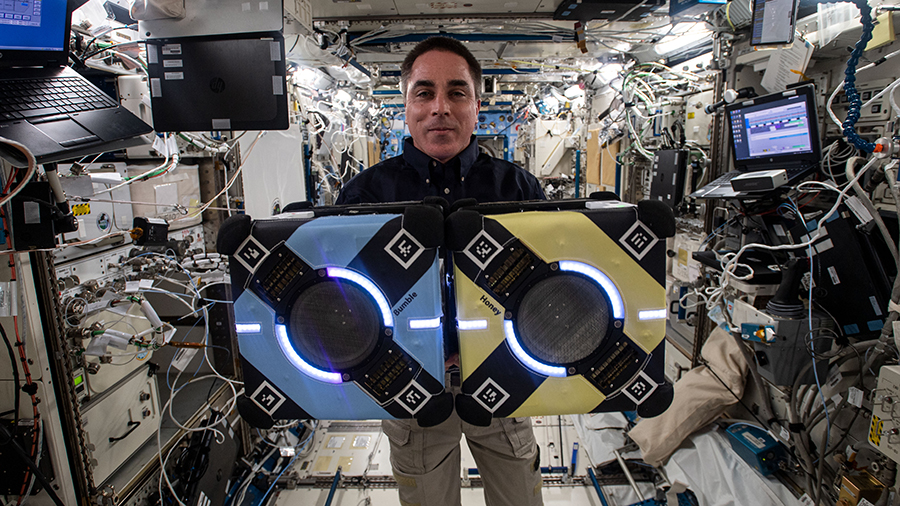 Expedition 63 Commander Chris Cassidy poses with two Astrobee robotic assistants during visual and navigation tests inside the Kibo laboratory module.