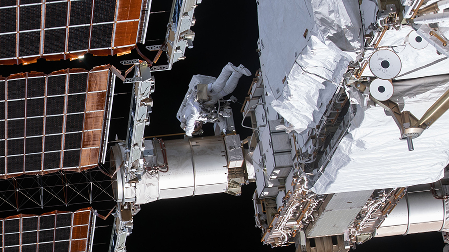 NASA spacewalker Flight Engineer Victor Glover is dwarfed by the main solar arrays on the International Space Station's far port-side truss structure.