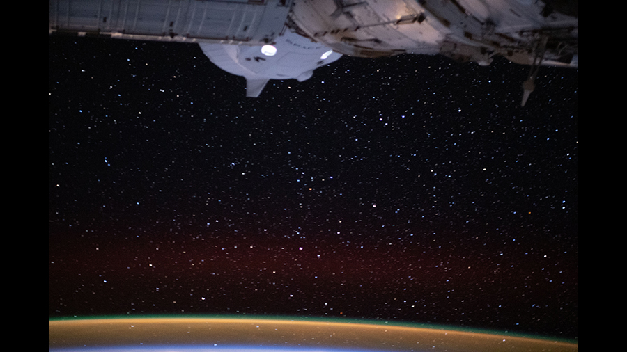 The SpaceX Crew Dragon spaceship, with its two lit crew windows, is pictured docked to the Harmony module's international docking adapter.