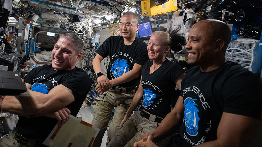 (From left) Michael Hopkins of NASA, Soichi Noguchi of JAXA (Japan Aerospace Exploration Agency), and NASA astronauts Shannon Walker and Victor Glover gather around a laptop computer to watch a movie inside the U.S. Destiny laboratory module.