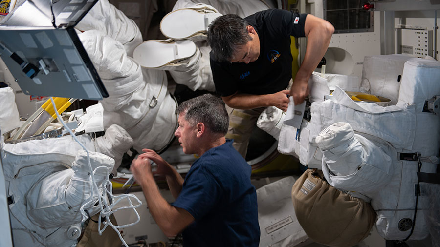 Expedition 65 astronauts Shane Kimbrough and Akihiko Hoshide perform maintenance on a pair of U.S. spacesuits.