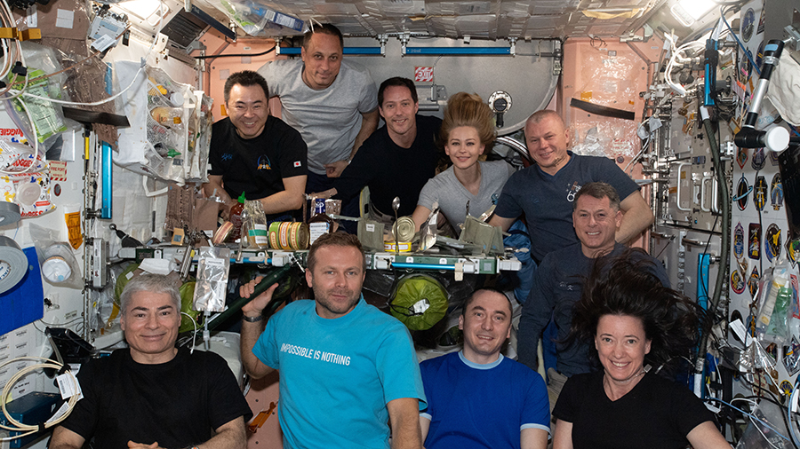 The ten station inhabitants are gathered together in the Unity module for a meal and a portrait. In the front row (from left) are, Mark Vande Hei, Klim Shipenko, Pyotr Dubrov, and Megan McArthur. In the back row (from left) are, Akihiko Hoshide, Anton Shkaplerov, Thomas Pesquet, Yulia Peresild, Oleg Novitskiy, and Shane Kimbrough.