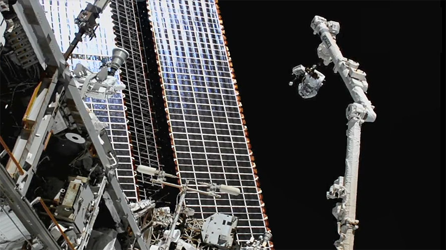 NASA spacewalker Thomas Marshburn rides the Canadarm2 robotic arm to the worksite to replace a station antenna system.