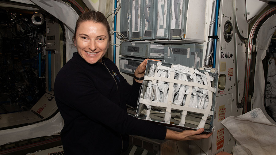 NASA astronaut Kayla Barron shows off food packets and prepares for lunch aboard the space station's Unity module.