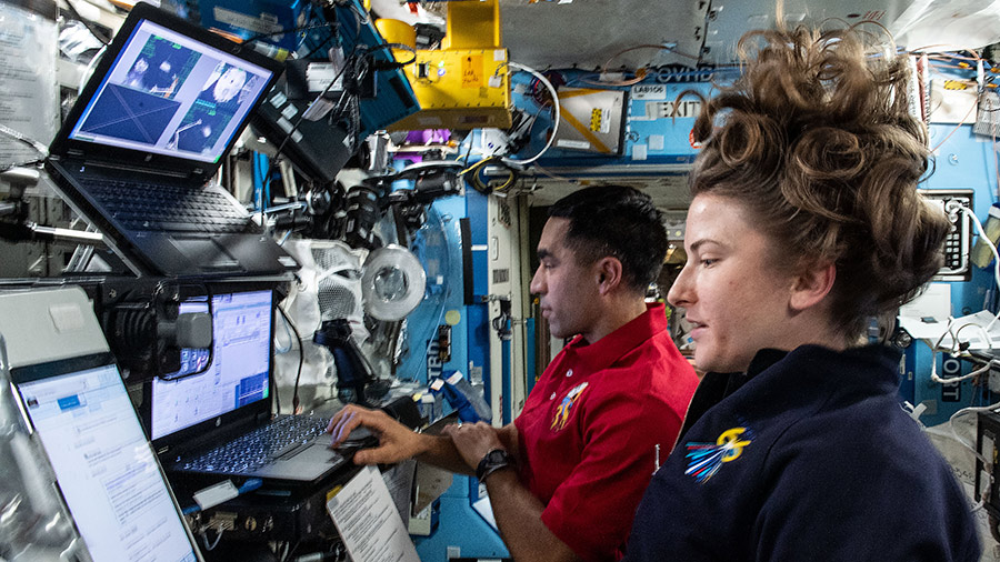 Astronauts Raja Chari and Kayla Barron train on the robotics workstation for the capture of the Cygnus space freighter when it arrives on Feb. 21, 2022.