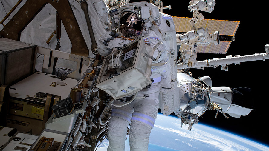 NASA spacewalker Raja Chari is pictured tethered to the space station with the SpaceX Crew Dragon Endurance behind him and the Atlantic coast of South America 268 miles below.