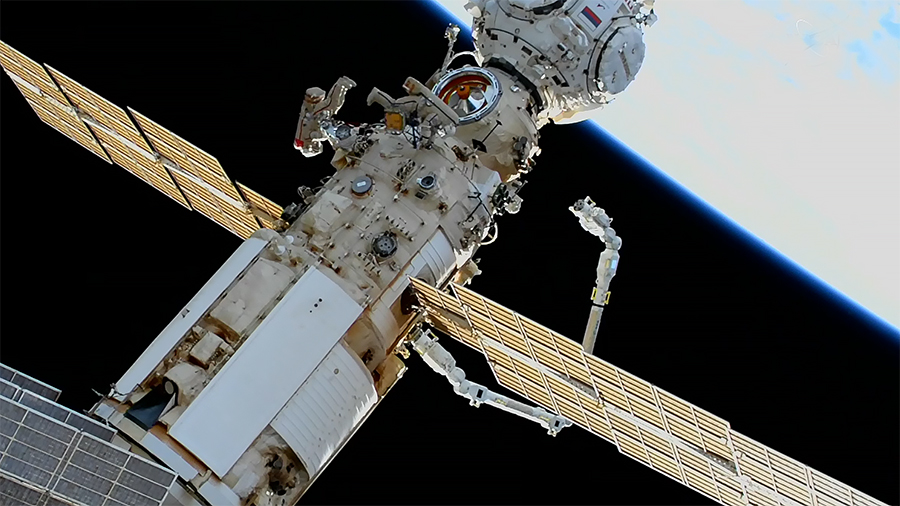 Spacewalkers Oleg Artemyev and Denis Matveev monitor the station's new European robotic arm as it moves on the Nauka multipurpose laboratory module.