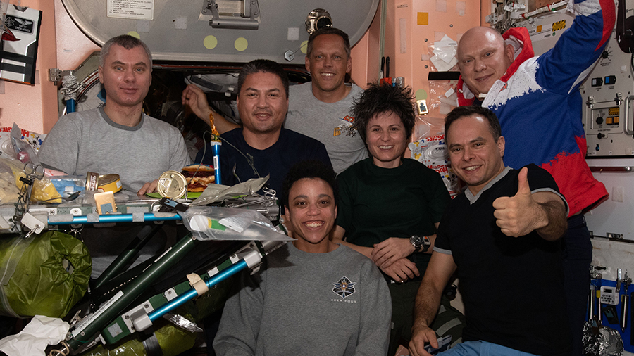 The Expedition 67 crew poses together for a portrait during dinner time inside the International Space Station's Unity module.