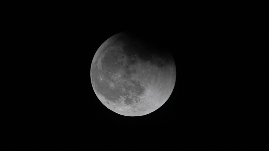 The Moon, with Earth's shadow draping across it during a lunar eclipse, is pictured from the International Space Station.