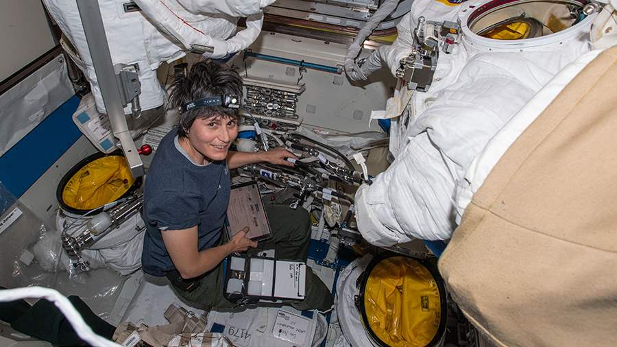 Astronaut Samantha Cristoforetti works on U.S. spacesuits inside the International Space Station's Quest airlock.