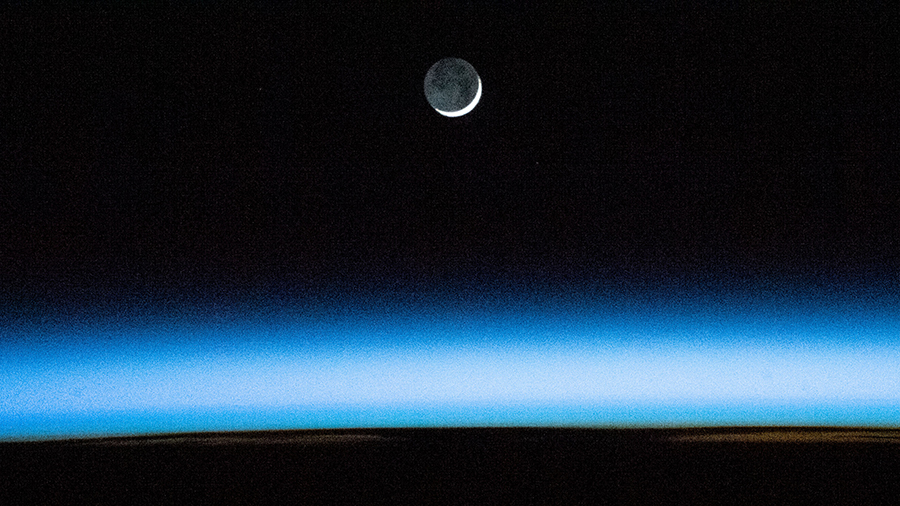 The waxing crescent Moon is pictured above Earth's atmosphere illuminated by an orbital sunset as the International Space Station flew 258 miles above the Atlantic Ocean.