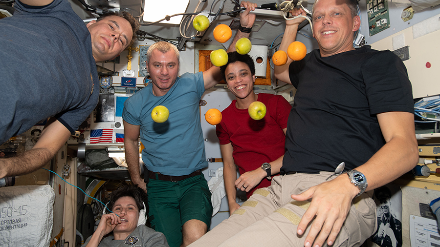 Expedition 67 crew members pose with fresh fruit flying weightlessly in microgravity delivered recently aboard the Progress 81 cargo craft