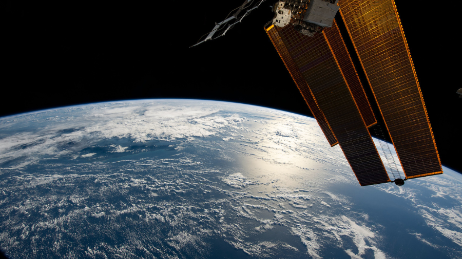 The sun's glint beams off the Coral Sea northeast of Australia as the International Space Station orbited 264 miles above on July 11, 2022. Pictured in the right foreground, are a pair of the station's main solar arrays and a radiator.