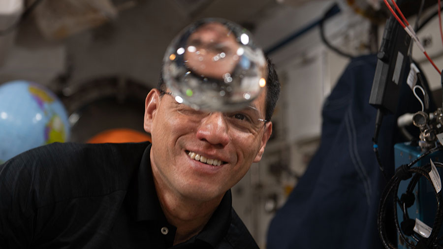 Astronaut Frank Rubio has fun with fluid physics as he observes the behavior of a free-flying water bubble inside the space station.