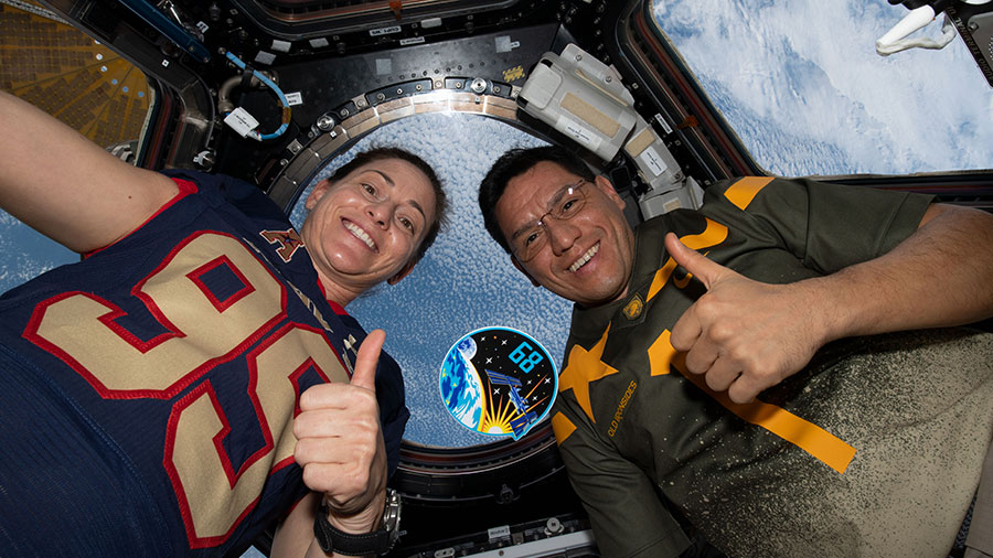 Astronauts Nicole Mann and Frank Rubio pose with their mission's insignia inside the cupola as the space station orbited above the Pacific Ocean.