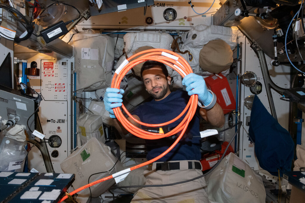 UAE (United Arab Emirates) astronaut and Expedition 69 Flight Engineer Sultan Alneyadi organizes cables inside the International Space Station's Harmony module.