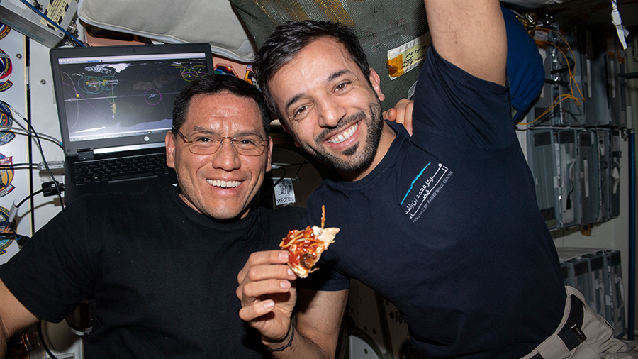 Expedition 69 astronauts (from left) Frank Rubio and Sultan Alneyadi pose for a portrait during pizza night aboard the International Space Station.