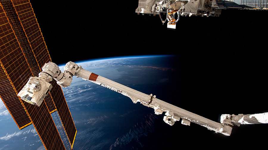 The space station soars above the coast of Argentina into an orbital sunset. From left are, the station's main solar arrays, the Canadarm2 robotic arm, and an external research platform.