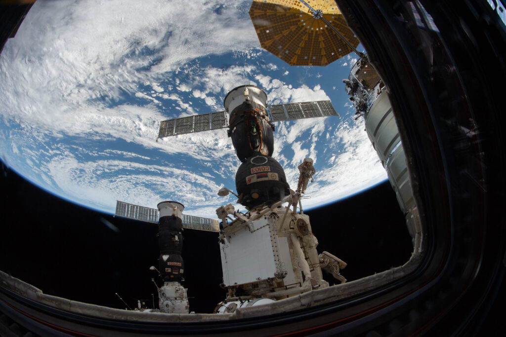 Roscosmos spacewalker Oleg Kononenko (suit with red stripes) attached to the Strela boom outside the International Space Station about 250 miles above Earth during a spacewalk on Dec. 11, 2018.