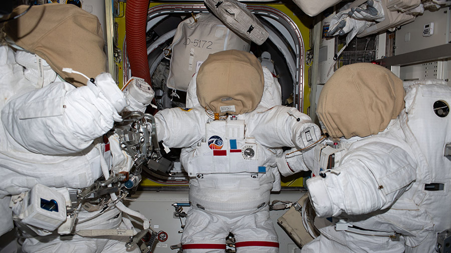 Three spacesuits are pictured inside the space station's Quest airlock in preparation for upcoming spacewalks.