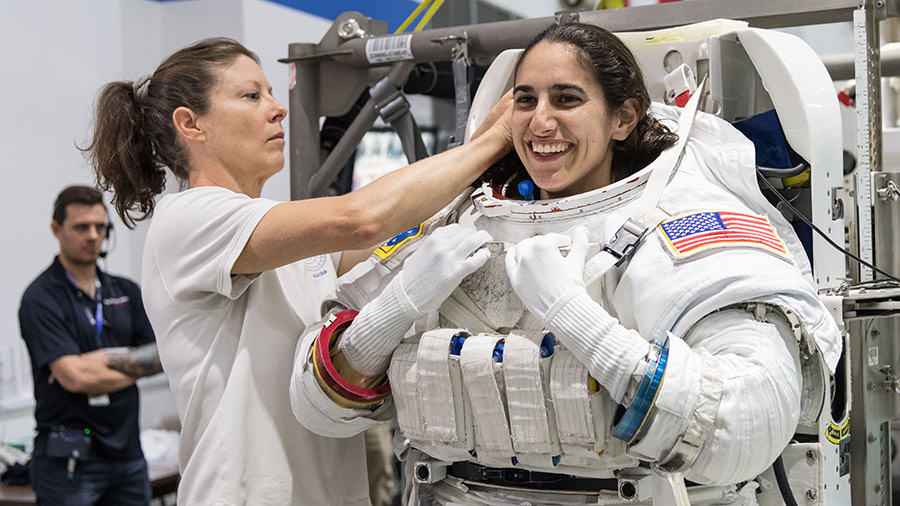 Astronaut Jasmin Moghbeli prepares for spacewalk training at Johnson Space Center’s Neutral Buoyancy Laboratory with assistance from astronaut Tracy C. Dyson.