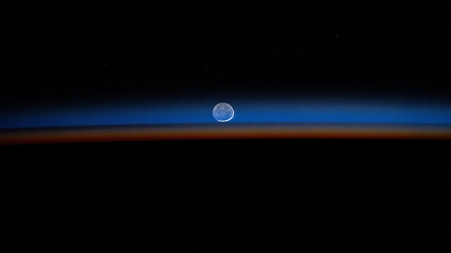 The New Moon sets behind Earth's colorful, but dimming atmosphere in this long-duration photograph taken with a camera programmed for high sensitivity.