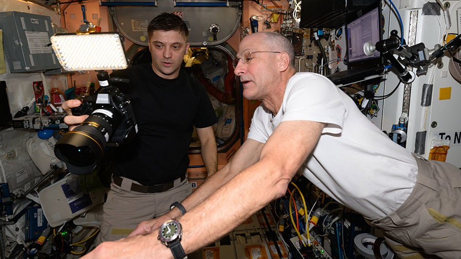 Expedition 71 Flight Engineers (from left) Matthew Dominick and Don Pettit, both from NASA, check out a digital camera aboard the space station's Unity module.