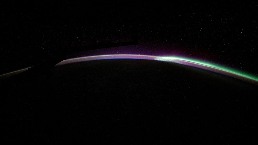 The aurora australis blends with Earth's atmospheric glow blanketing the nighttime horizon in this photograph from the space station as it orbited above the Pacific Ocean.