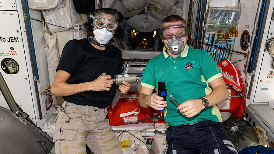 Astronaut Suni Williams (left) and cosmonaut Aleksandr Gorbunov pose for a portrait wearing personal protective equipment before entering the SpaceX Dragon cargo spacecraft.