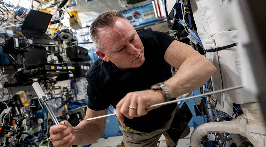 Astronaut Butch Wilmore installs portable experiment hardware inside the Destiny laboratory module aboard the International Space Station.