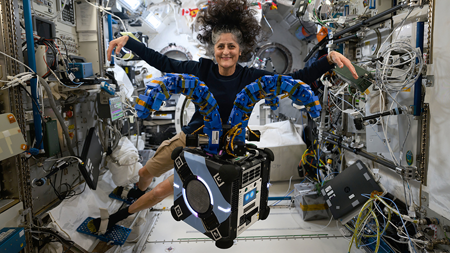 Astronaut Suni Williams checks out the Astrobee robotic free-flyer outfitted with tentacle-like arms containing gecko-like adhesive pads to demonstrate satellite capture techniques.