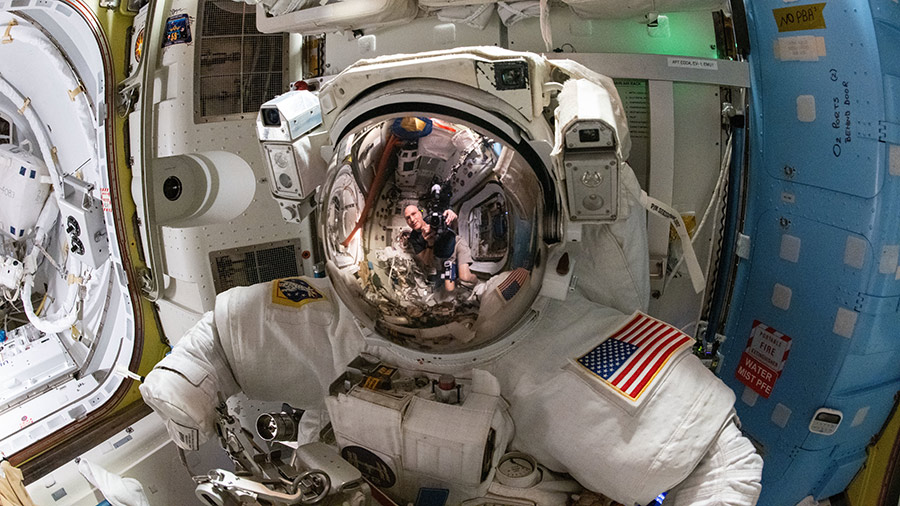 Astronaut Don Pettit's reflection is pictured on the helmet visor of a spacesuit in this photograph he took inside the Quest airlock.