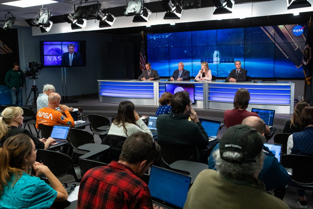 Dustin Cammack, NASA Communications, far left, moderates a prelaunch news conference on Dec. 3, 2019, for SpaceX's 19th Commercial Resupply Services (CRS-19) mission for NASA to the International Space Station, at the agency’s Kennedy Space Center in Florida. Speaking to members fo the news media are, from left, Bryan Dansbury, assistant program scientist, International Space Station Program Science Office at NASA; Jessica Jensen, director, Dragon Mission Management at SpaceX; and Mike McAleenan, launch weather officer, U.S. Air Force 45th Space Wing.