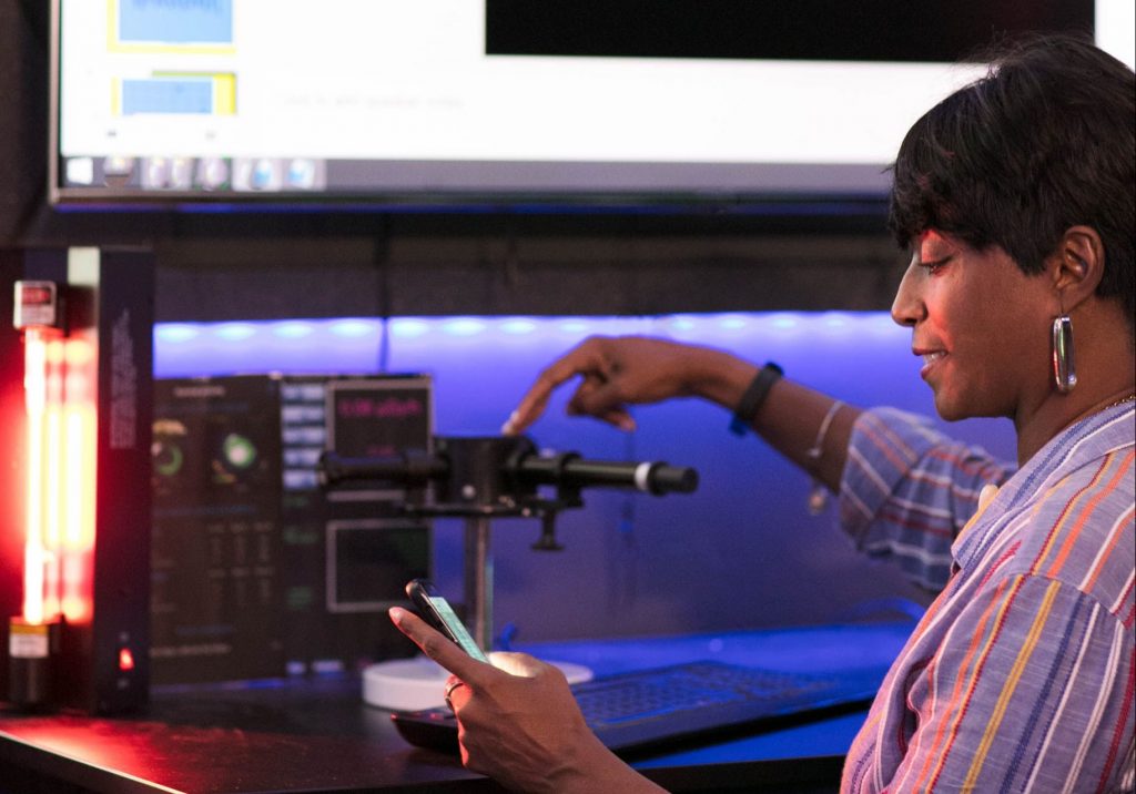 Leslie Garrison sits in front of a 3D printer in the STEAM Innovation Lab.