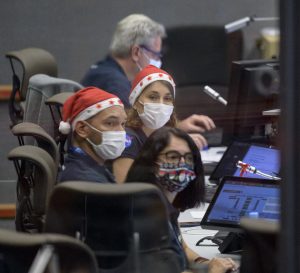 Launch teams wearing Santa hats monitor the Webb telescope countdown from a control room.