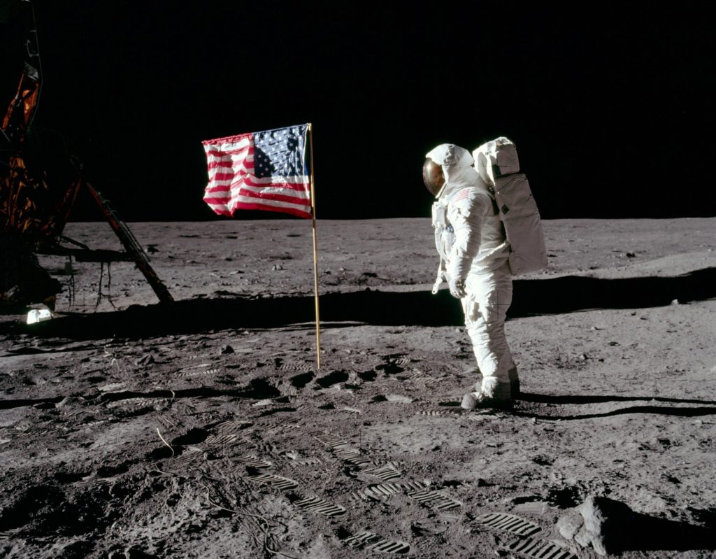 Astronaut Edwin E. Aldrin Jr., lunar module pilot of the first lunar landing mission, poses for a photograph beside the deployed United States flag during an Apollo 11 extravehicular activity (EVA) on the lunar surface. 