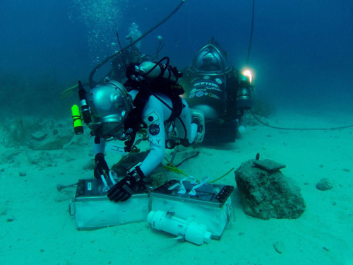 Photo of JAXA astronaut Kimya Yui collects chipping samples from a rock simulating an asteroid boulder.