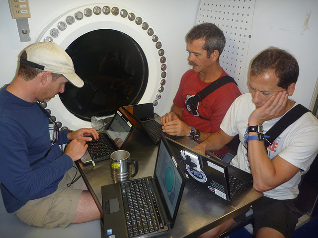 The NEEMO crew sitting at a table working on laptop computers The NEEMO crew sitting at a table working on laptop computers