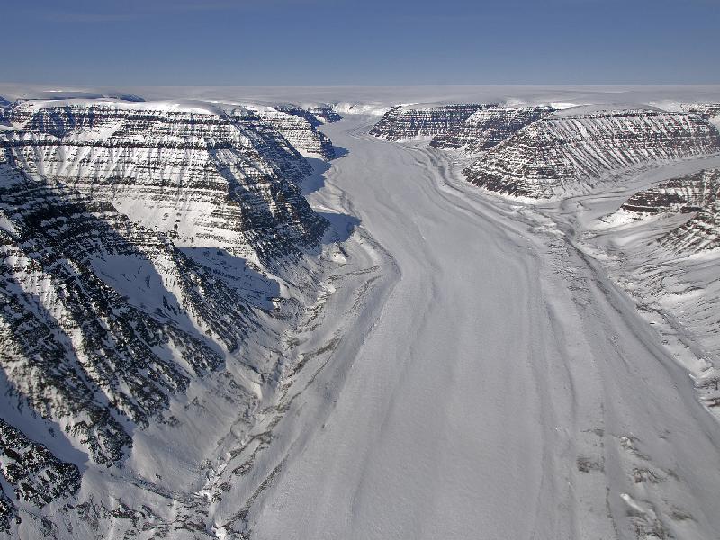 A glacier between mountains on Greenland's Geikie Peninsula. The mountains on the Geikie Peninsula in Greenland consist mostly of flood basalts formed during the opening of the North Atlantic Ocean millions of years ago.