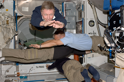 Four crew members float through the space station in four different directions.